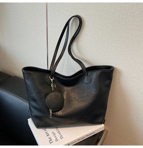 Detail of black leather tote bag with round coin purse and golden zipper hardware