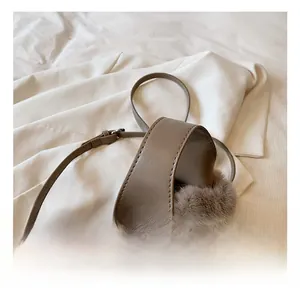 Détail du sac seau en peluche café avec poignée en cuir et accessoires métalliques