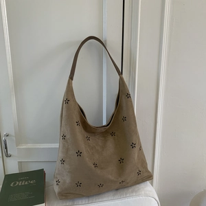 Detailed view of laser-cut flower patterns on brown faux suede hobo tote bag