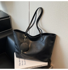 Detail of black leather tote bag with a matching round coin purse on a book