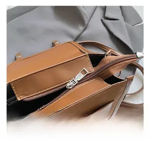 Detail showing the silver metal zipper and black fabric lining of the brown leather bag