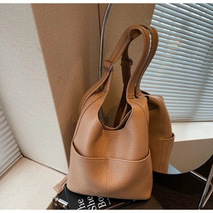 Detail of light brown lychee grain leather bucket bag with front pockets and strap