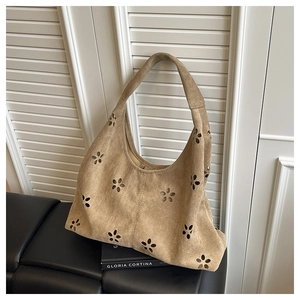 Détail du motif floral ajouré au laser sur le sac hobo en daim de couleur camel