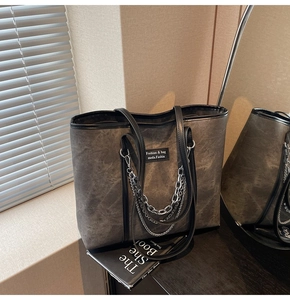 Détail d'un grand sac cabas gris avec chaînes argentées multicouches et anses noires