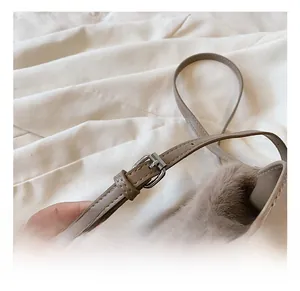 Détail de la bandoulière en cuir réglable avec boucle en métal sur le sac seau en peluche
