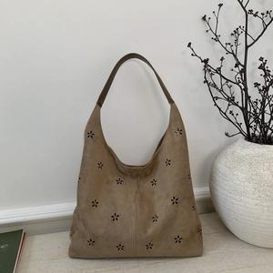 Detailed view of khaki suede tote bag with intricate laser-cut floral patterns