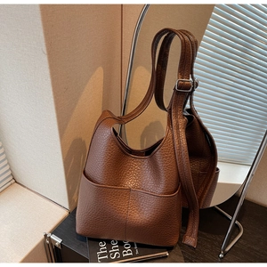 Detail of a brown lychee-textured leather hobo bag with dual front pockets and silver buckle