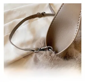 Détail du crochet métallique et de la bandoulière en cuir sur un sac seau en peluche