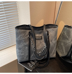 Gros plan sur un sac cabas en toile grise avec chaîne argentée et cuir