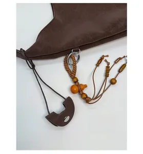 Detailed close-up of dark brown leather bucket bag with vintage wooden bead charms