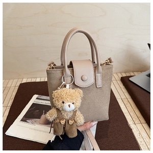 Detailed shot of khaki matte leather handbag with plush bear charm and gold hardware
