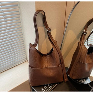Detail of dark brown pebble leather bucket bag featuring elegant stitching and adjustable strap