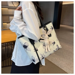 Dettaglio della borsa tote in tela crema con stampe a farfalla e ciondolo a forma di coniglio
