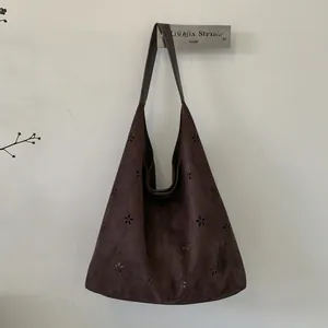 Close-up of laser-cut floral patterns on dark brown suede tote with large capacity