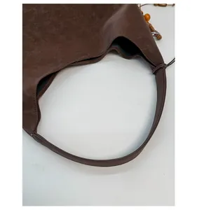 Detail of dark brown faux leather tote with litchi texture and wooden bead charm