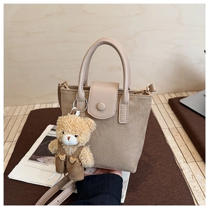 Detailed close-up of apricot suede mini tote bag with cute plush bear charm accessory