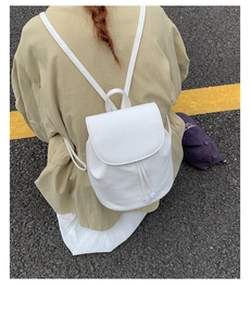 Detail of white faux leather backpack featuring drawstring closure with decorative beads