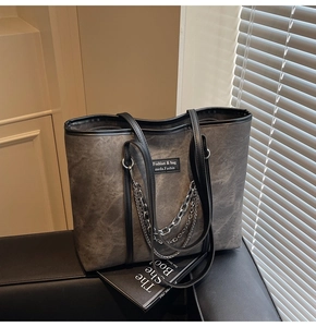 Détail du sac cabas vintage gris foncé avec chaînes argentées sur cuir noir