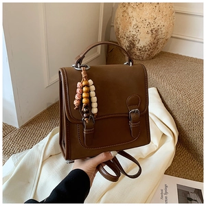 Macro view of vintage brown leather backpack with colorful beaded tassel detail