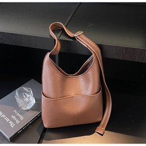 Close-up of brown litchi pattern leather bag with wide strap and front pocket detail