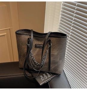 Détail d'un sac cabas gris vintage avec décoration de chaînes métalliques argentées multicouches