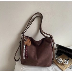 Nahaufnahme braune Beuteltasche aus weichem Leder mit Markenlogo und Plüschbär-Anhänger