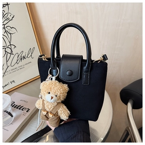 Detail of black suede mini bag with cute teddy bear charm and gold metal hardware