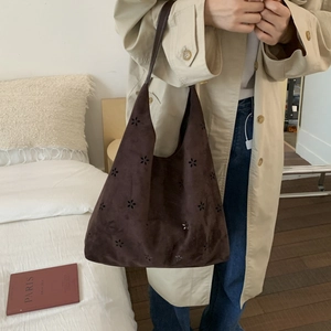 Detailed view of dark coffee suede tote bag with laser-cut floral hollow pattern