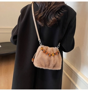 Detailaufnahme der hellbraunen Plüschtasche mit Bernsteinperlen und Lederriemen-Details