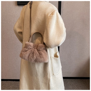 Détail d'un sac seau en fausse fourrure rose poudré avec bandoulière en cuir pour l'hiver