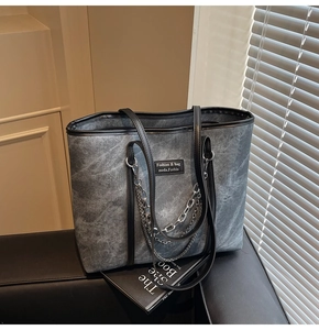 Détail du sac cabas en denim délavé gris avec chaîne argentée et poignées en cuir noir
