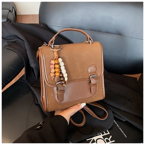 Detail view of brown vintage PU leather backpack with decorative wooden bead charm