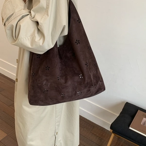 Detail view of laser-cut flower patterns on dark brown suede hobo tote bag for women