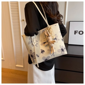 Dettaglio della borsa tote bianco sporco con stampe floreali blu e ciondolo a coniglio