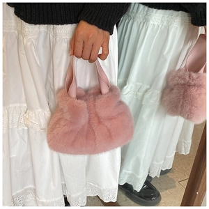 Détail d'un sac seau rose en peluche en fausse fourrure douce avec poignée en cuir
