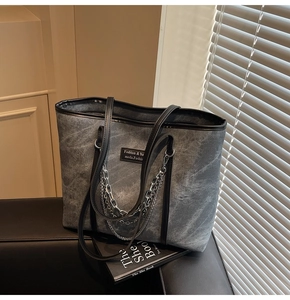 Détail du sac cabas en toile grise vintage avec bordure en cuir noir et chaînes