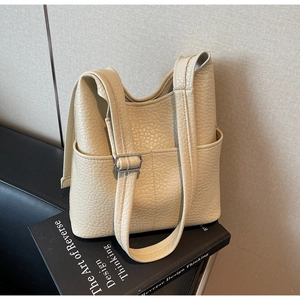 Detail of cream leather bucket bag showing side pockets and silver shoulder strap buckle