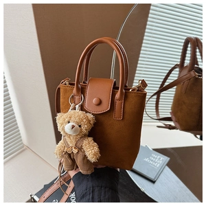 Brown matte suede bucket bag detail with a cute teddy bear charm and leather handle
