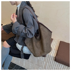 Detail shot of a dark brown suede oversized tote bag worn by a model for a vintage look