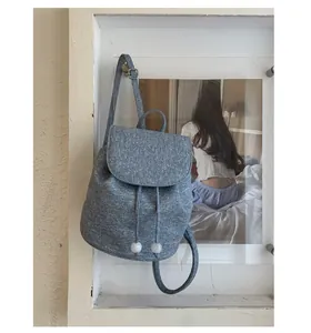 Detail of grey-blue textured fabric backpack with drawstring closure and bead accents