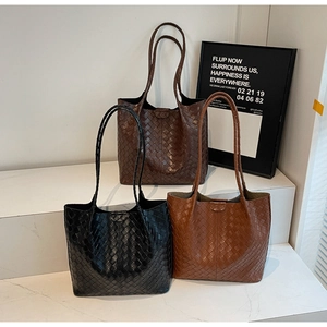 Detailed close-up of three woven tote bags in black, dark brown, and caramel colors
