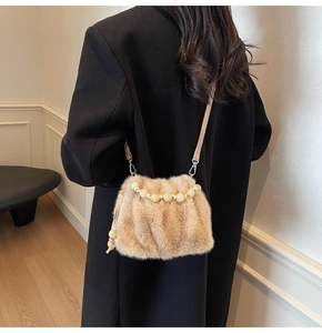Detail einer flauschigen Kunstfell-Handtasche mit elegantem Perlgriff und Lederriemen