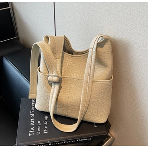 Macro shot of beige lychee texture faux leather bag with stitch detail and side pocket