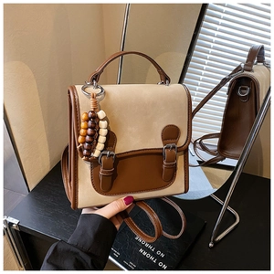Detail view of a vintage beige and brown backpack with leather straps and wooden pendant