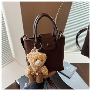 Detail of vintage suede bucket bag with a cute teddy bear charm and leather handle