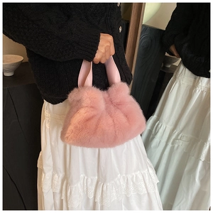Détail d'un sac seau en fausse fourrure rose avec texture douce et poignée en cuir