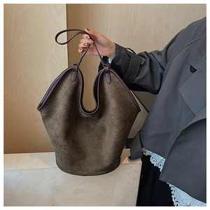 Detail view of large frosted suede bucket bag with leather handles and U-shaped opening