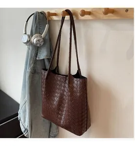 Close-up of dark brown woven tote bag hanging on a hook in a warm home setting
