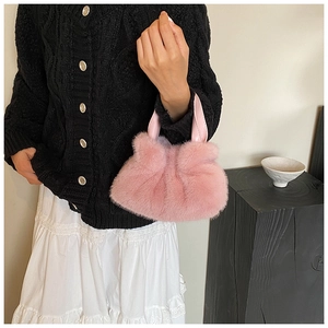 Détail du sac seau en fausse fourrure rose avec textures douces et anses en cuir