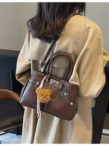 Vintage chocolate brown leather handbag with plush bear charm and contrast stitching